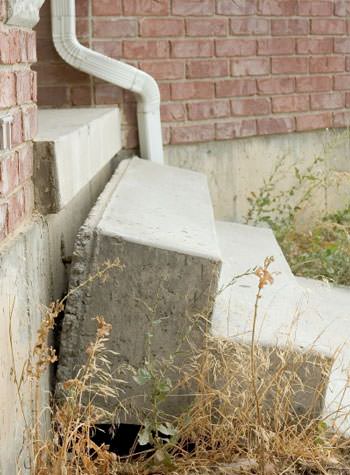 sinking outdoor concrete steps showing cracking and soil washout in Leland