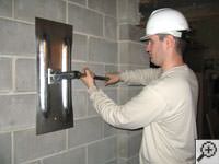 Attempting to straighten a bowed foundation wall by straightening a wall anchor system in a Camp Lejeune home.