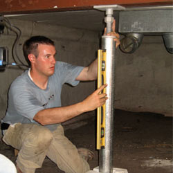 A contractor in Kinston installing a crawl space jack post.