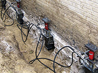 Using foundation push piers to lift a foundation during a repair in Lumberton.