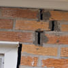A brick wall displaying stair-step cracks and messy tuckpointing on a Jacksonville home
