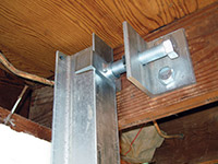 Securing the i-beam system to the top of the floor joist in a foundation wall repair in Camp Lejeune.