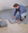 Contractors installing basement subfloor tiles and matting on a concrete basement floor in New Bern, North Carolina