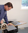 installing a waterproof vapor barrier on a basement floor to prepare for basement carpeting in a Jacksonville home